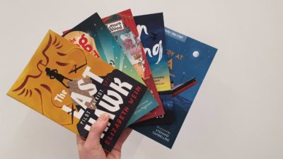 Hand holding 5 paperbacks, fanned out