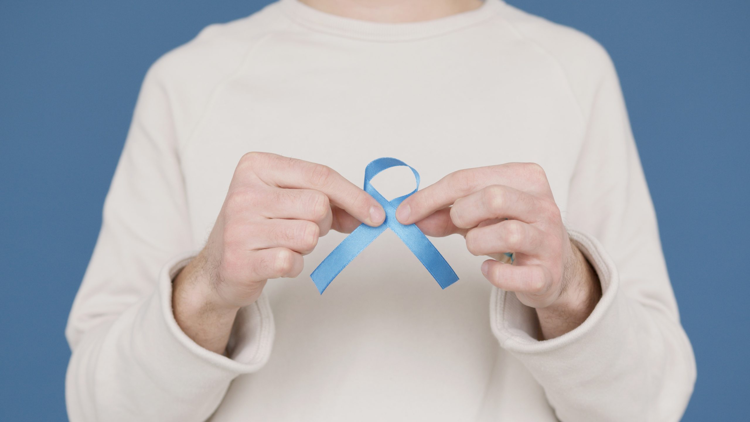 Hands holding a blue charity awareness ribbon.