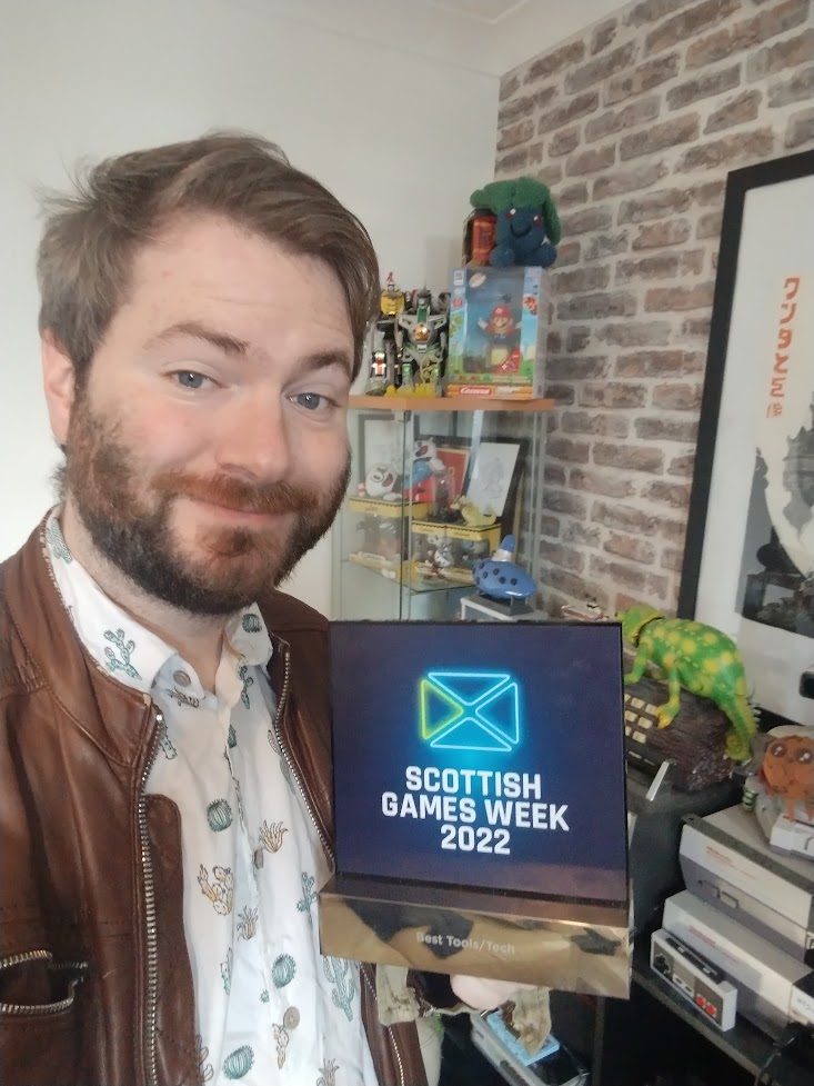 Games designer Alastair Lowe holds his Scottish Games Week 2022 winner's trophy.