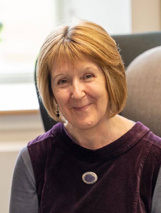 A head and shoulders shot of Dyslexia Scotland Cheif Executive Cathy Mgaee, smiling at the camera, in a plum-coloured, velvet top.