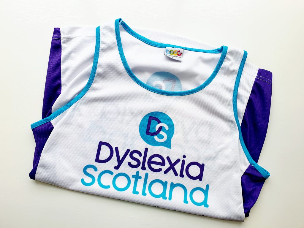 The vest folded so the front is showin g- the Dyslexia Scotland logo is on the white back; the sides of the vest are purple panels.