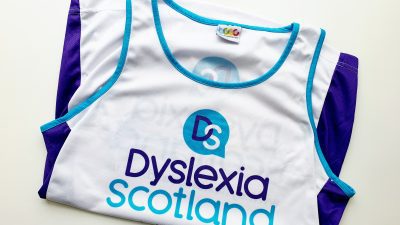 The vest folded so the front is showin g- the Dyslexia Scotland logo is on the white back; the sides of the vest are purple panels.