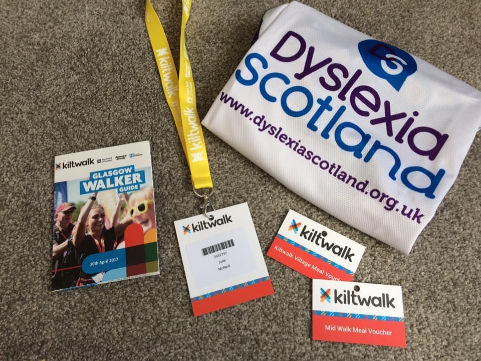 Dyslexia Scotland branded sports vest sits alongside KiltWalk branded tickets and lanyard.