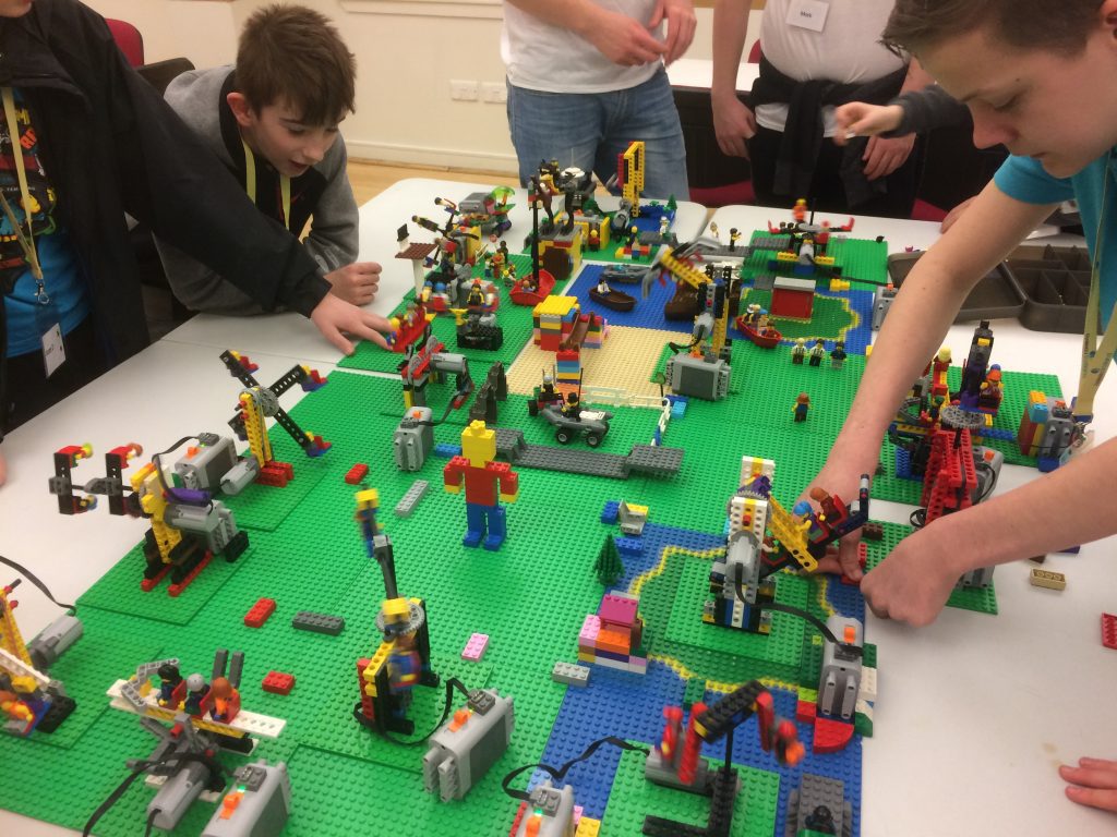 Young people arrange lego on a table.