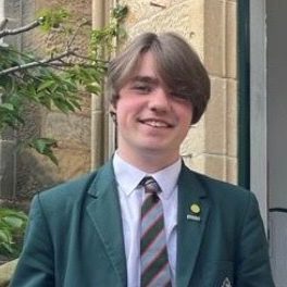 Monty wearing a green blazer and striped tie , smiles directly at us.