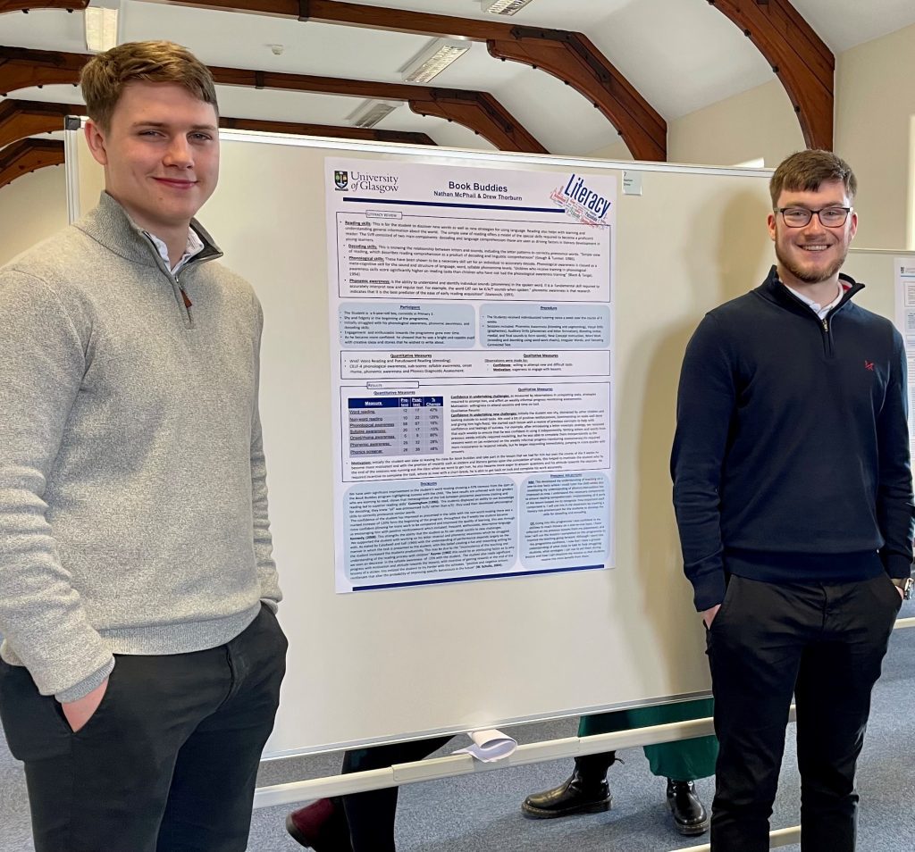 2 students flank their research poster on the Book Buddies scheme.