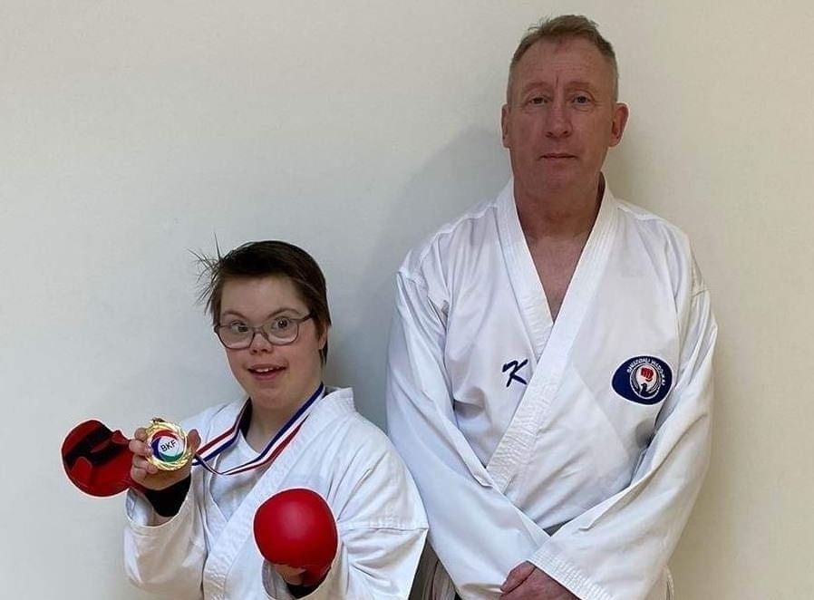 Karate instructor Andy Elliott with a young learner, both dressed in karate whites.
