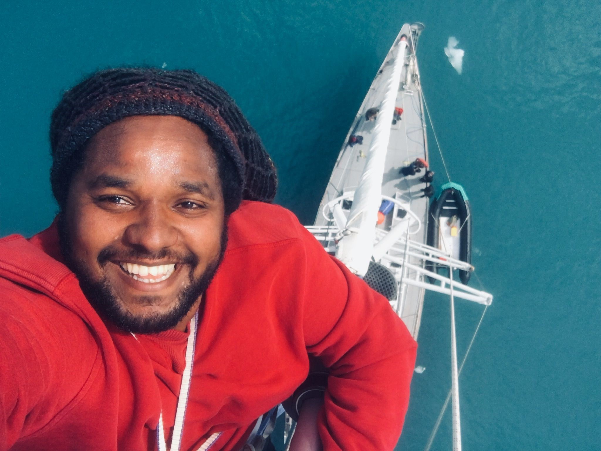 Hamza Yassin takes a selfie from the crow's nest of a boat, the hull and blue water visible in the background below.