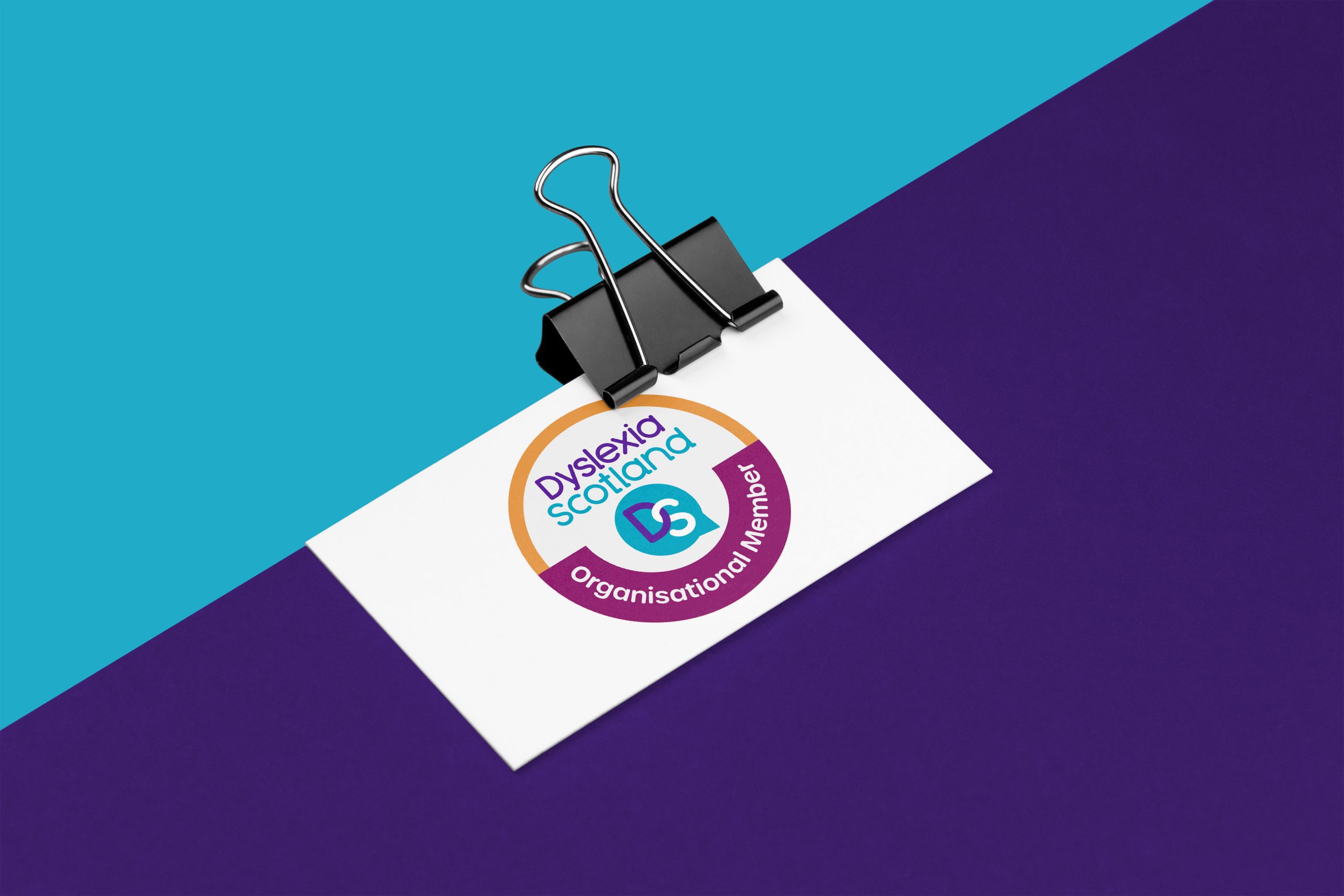 Business card with Dyslexia Scotland organisational member badge clipped to a purple paper.
