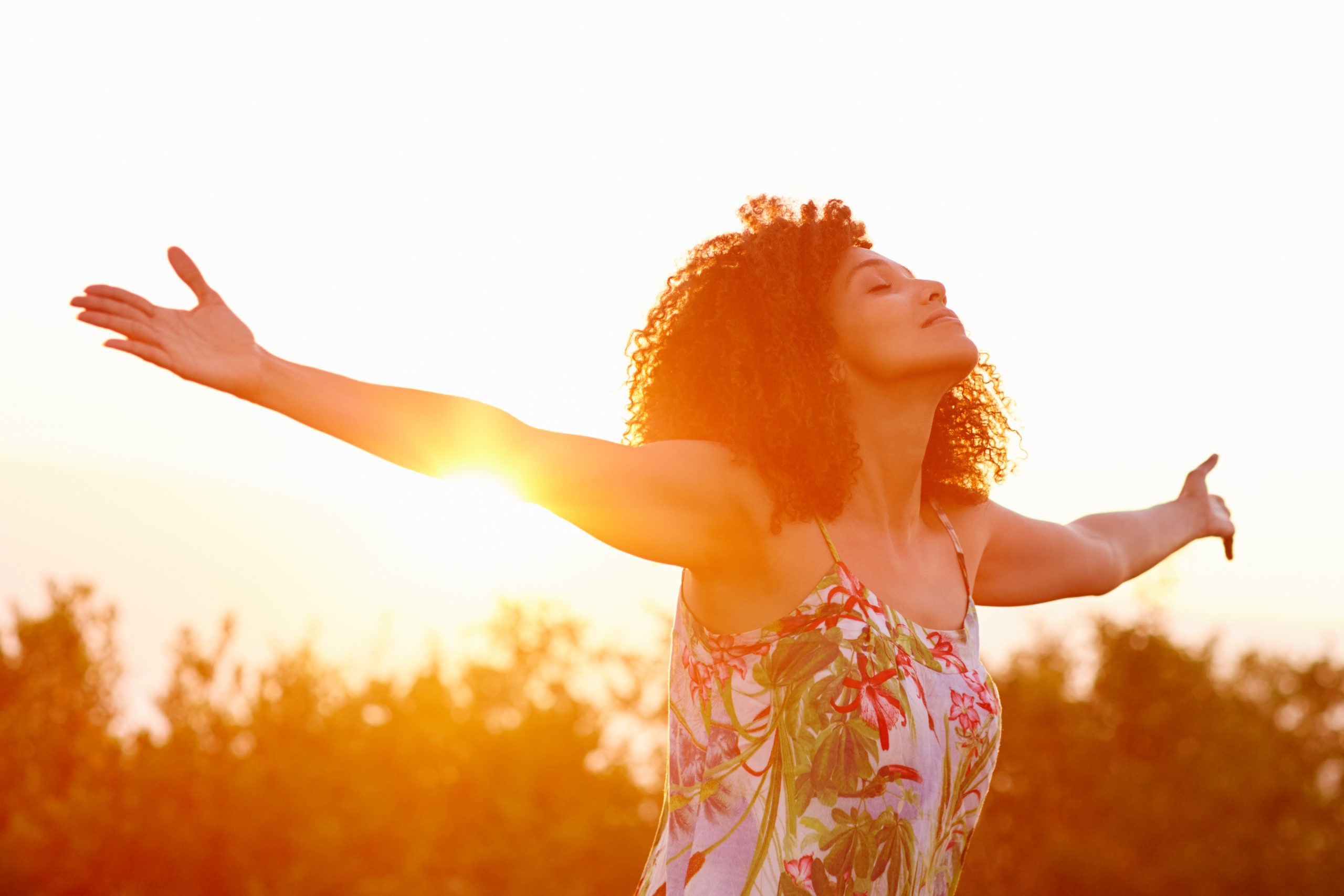 Woman with outstretched arms enjoys the feel of the sun on her back.