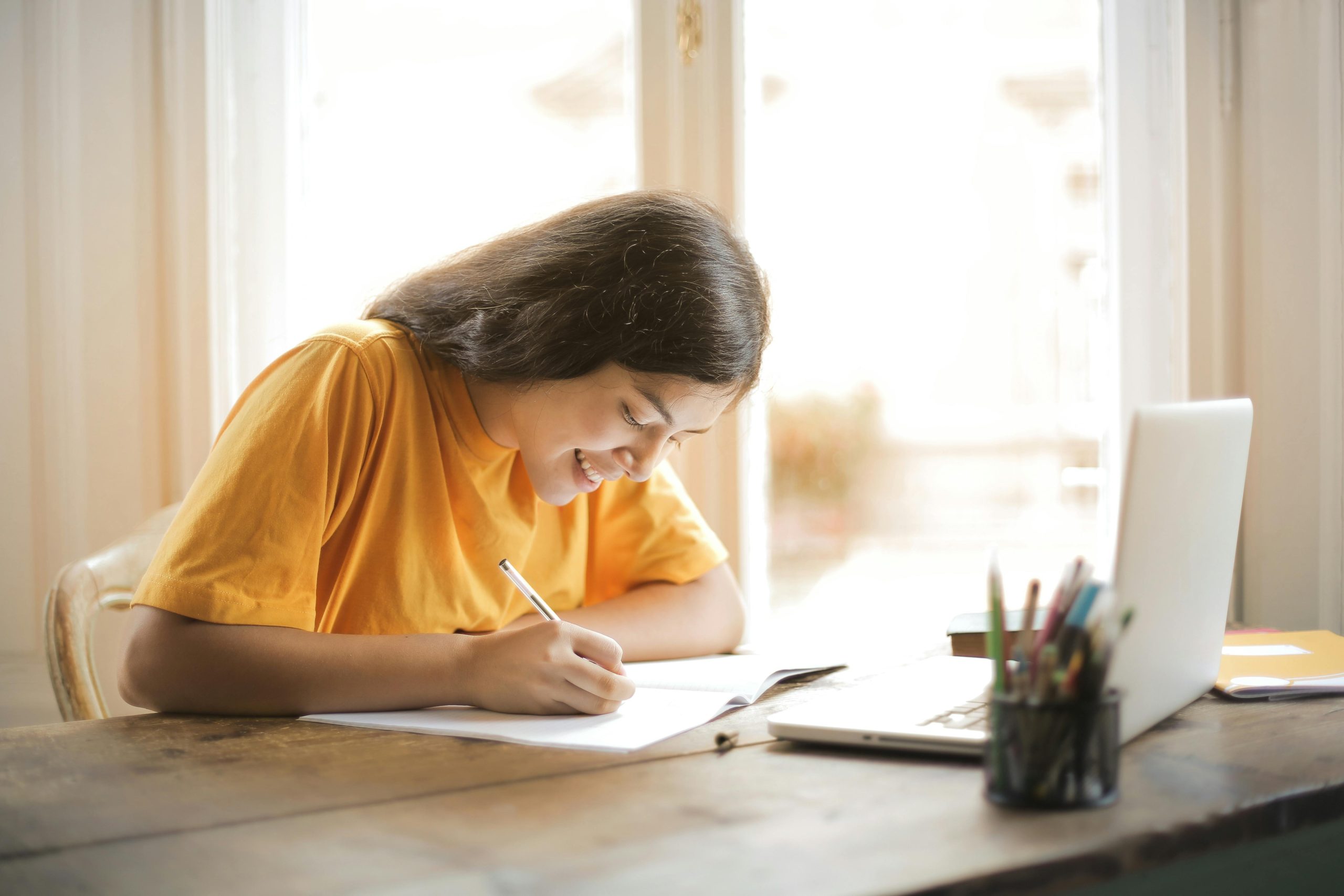 Girl smiling while writing in a notebook