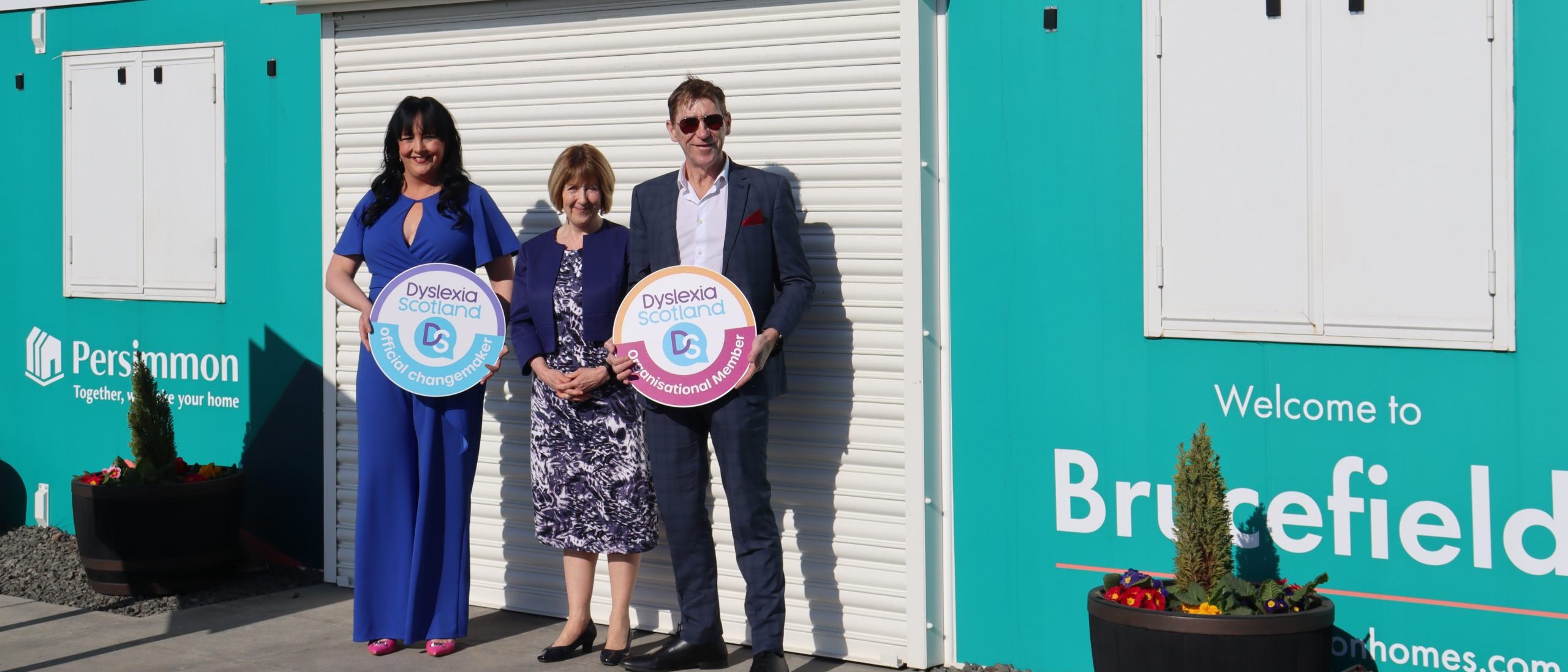 Representatives of Persimmon Homes hold Dyslexia Scotland signs at their Brucefileds site in Stirling, flanking Chief Executive of Dyslexia Scotland Cathy Magee.