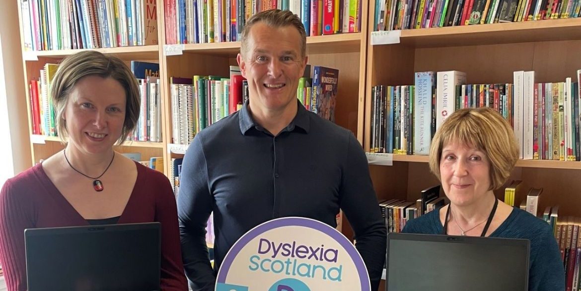 Xerox employee and Dyslexia Scotland staff hold up the laptops