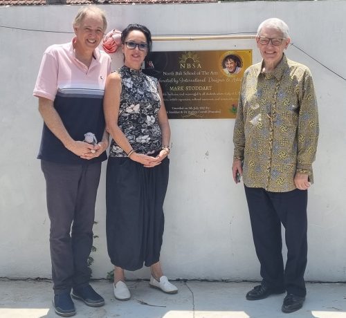 Marc with two colleagues by a wall plaque honouring his donation