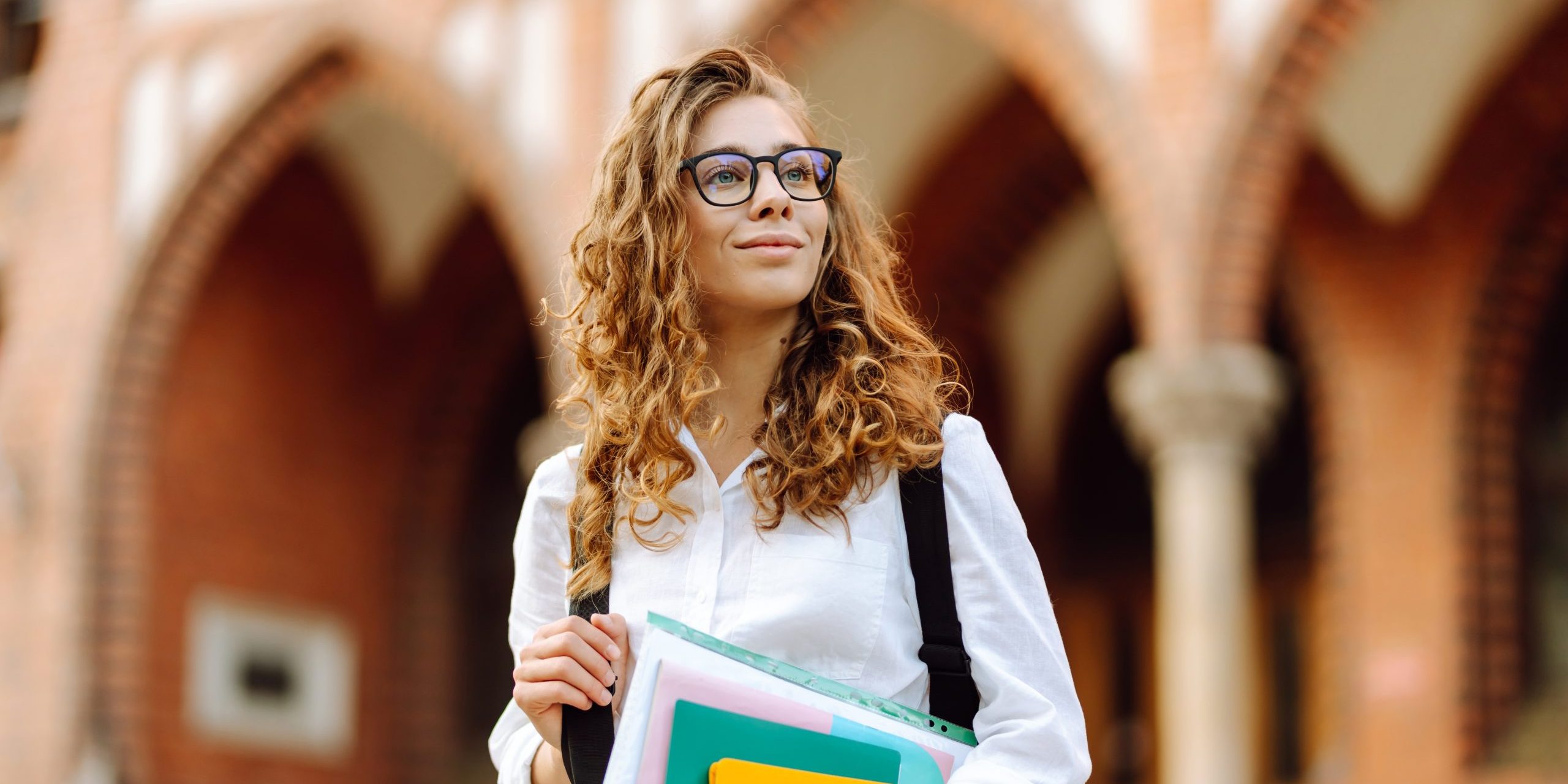 A student standing among the university cloisters