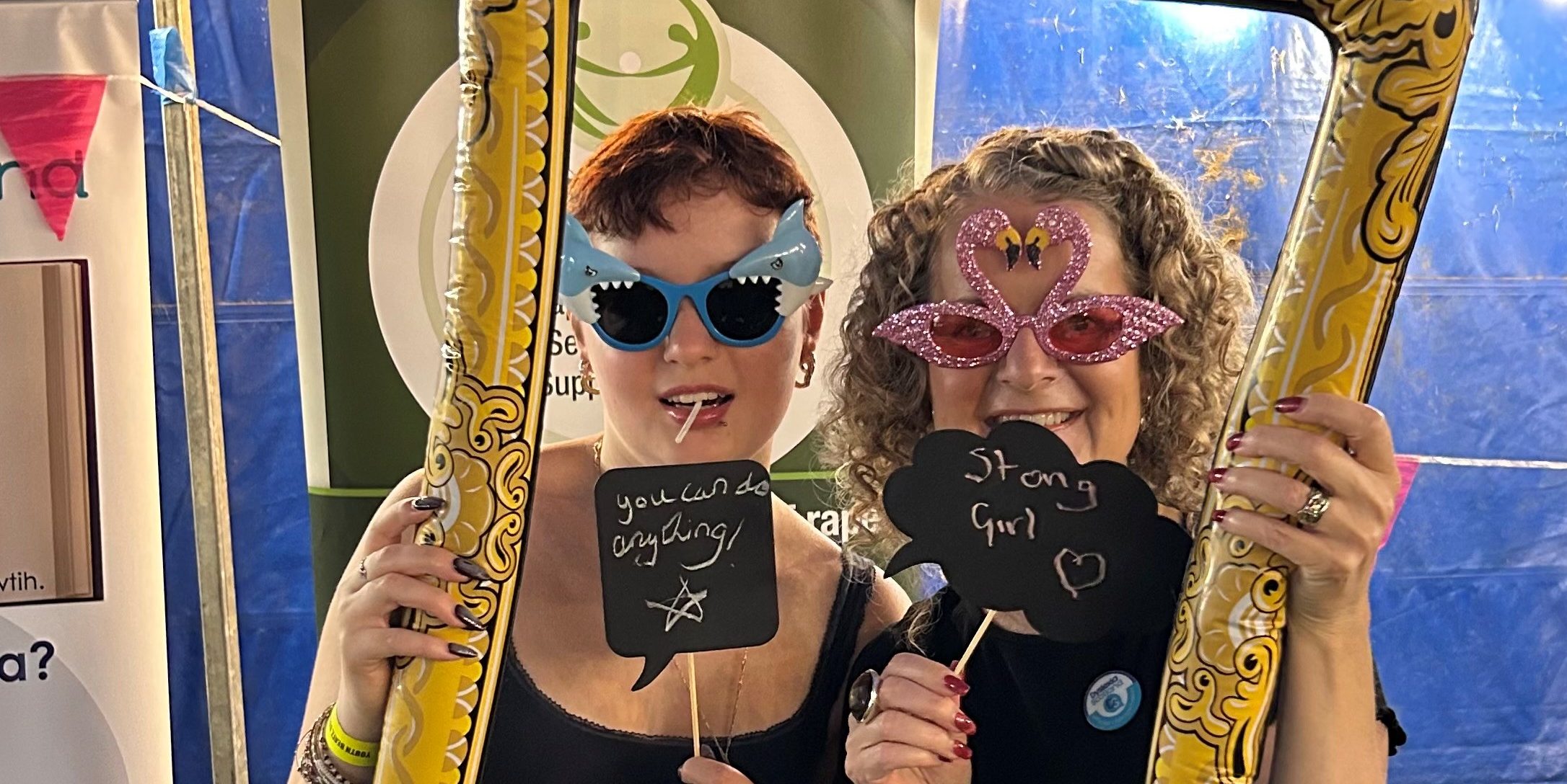Lucy and Anna in novelty sun glasses hold and look through an ornate brass frame