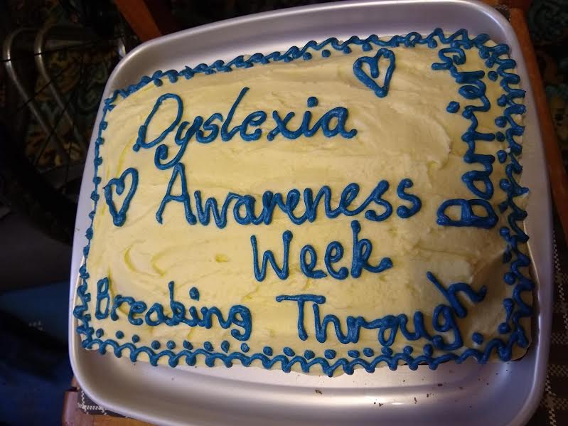 A hand decorated cake with piped icing that reads Dyslexia Awareness Week Breaking Through Barriers