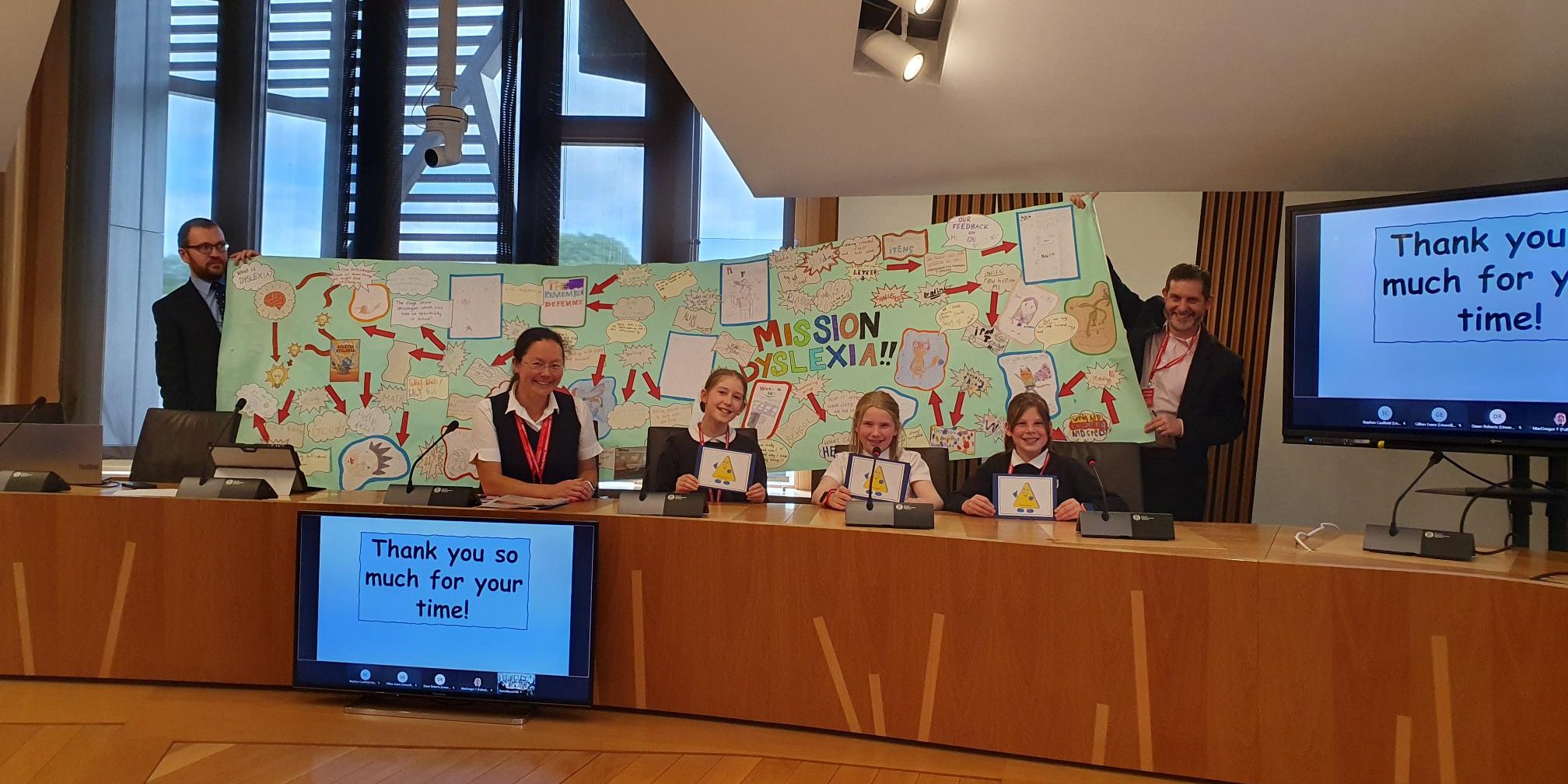 Young people and their teacher delivering a presentation in a committee room
