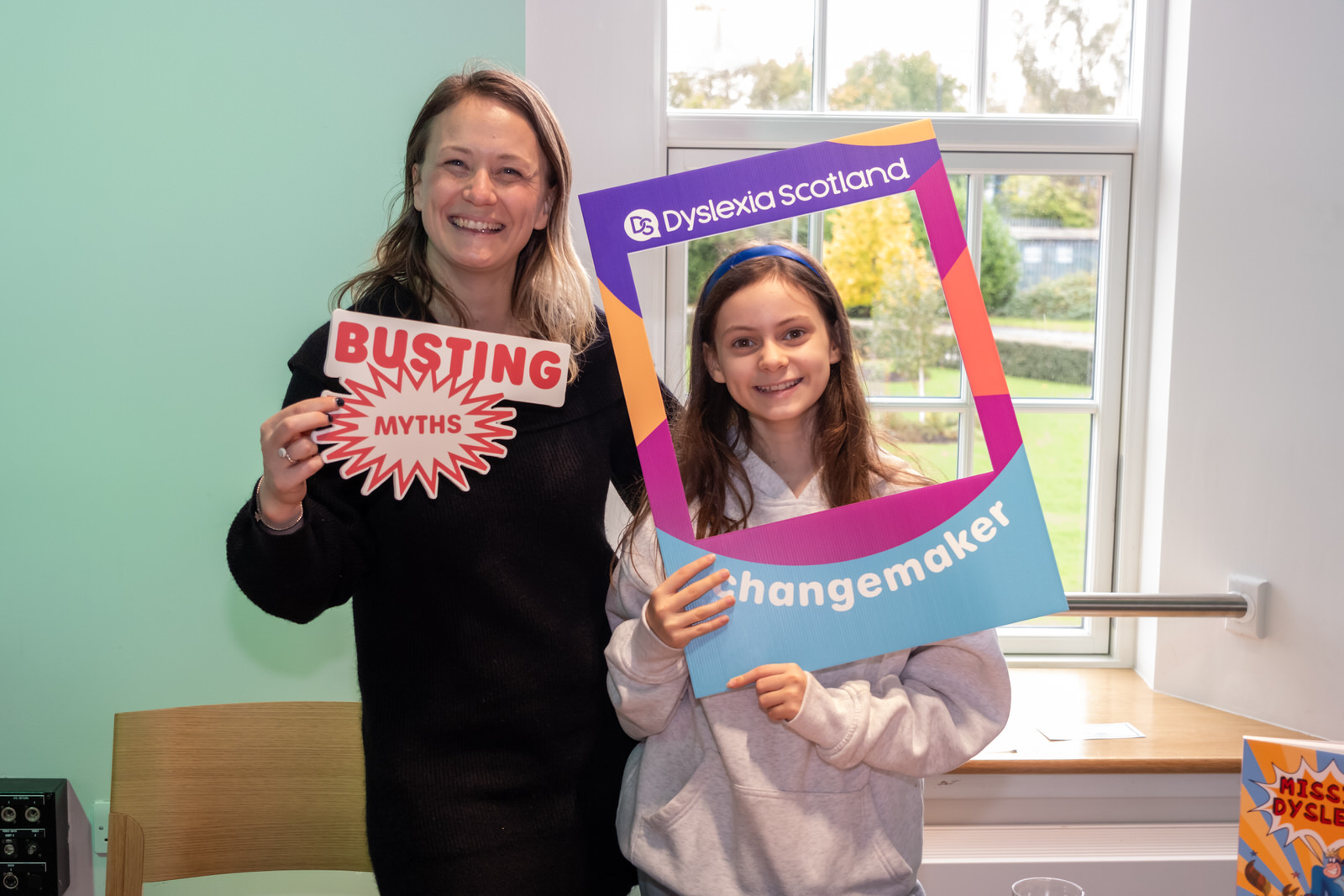 A woman and child hold Myth Buster and Changemaker signs