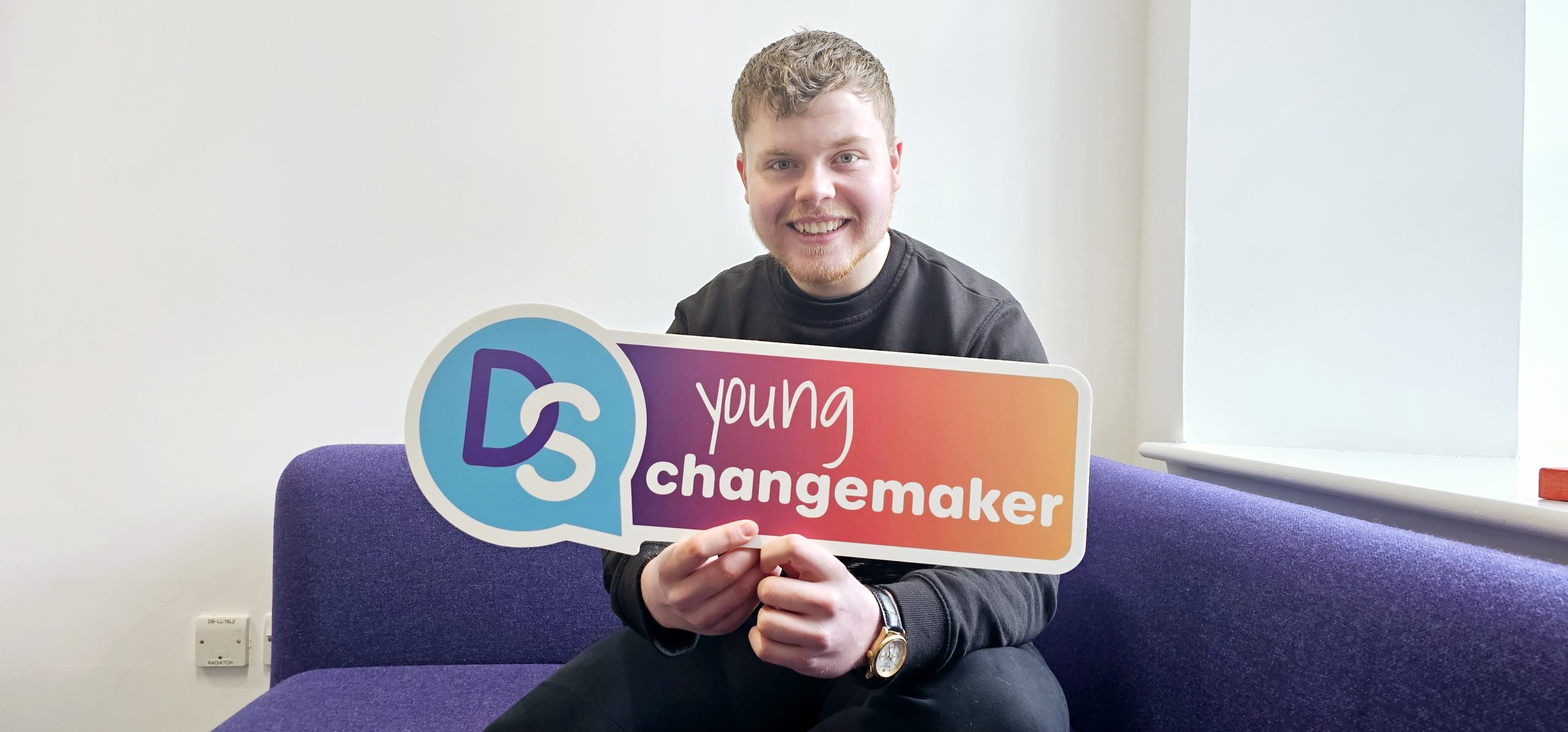 Young Ambassador Marc holding a Young Changemaker sign