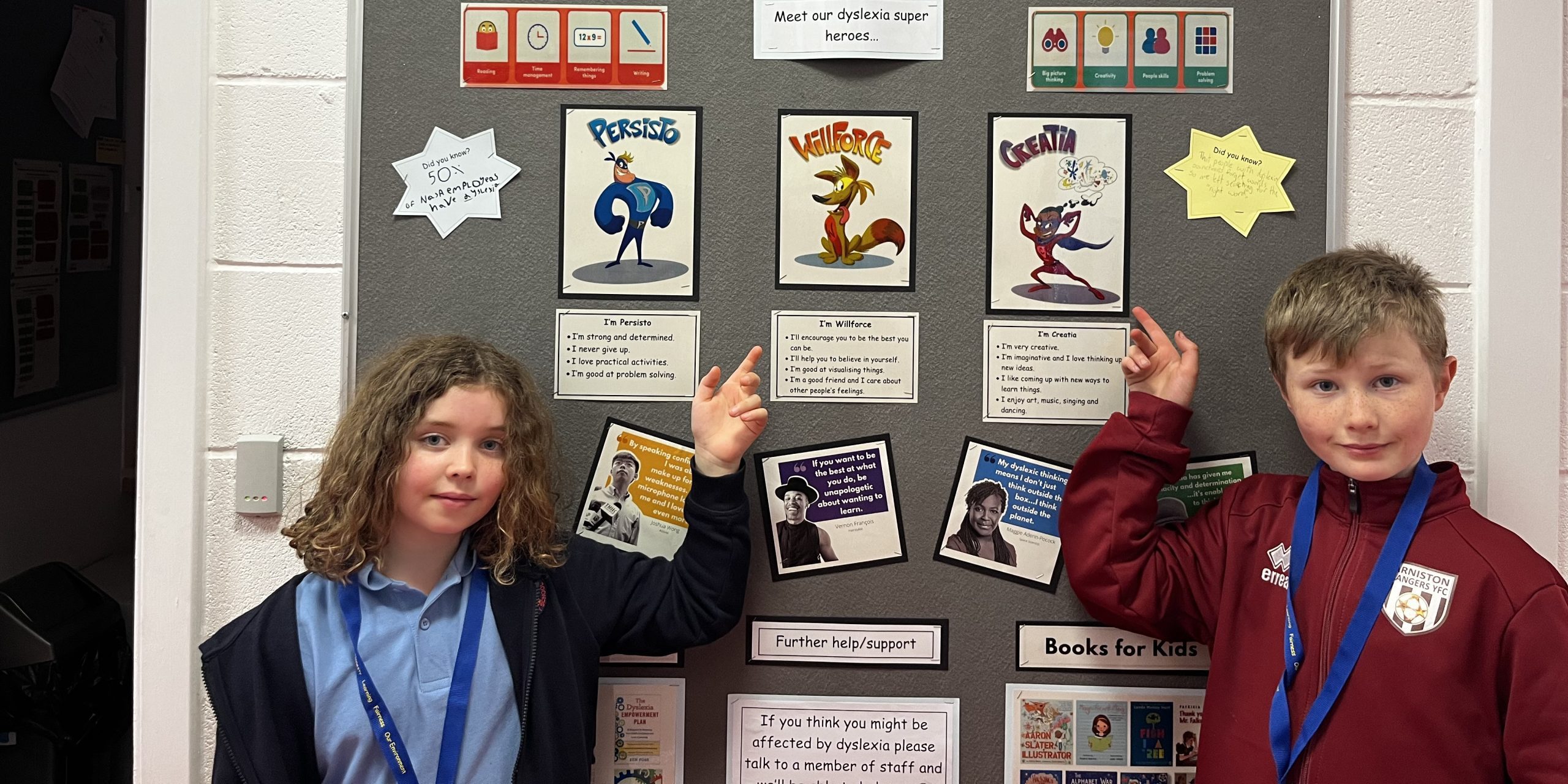 Two young people point to their school notice board with dyslexia resources on