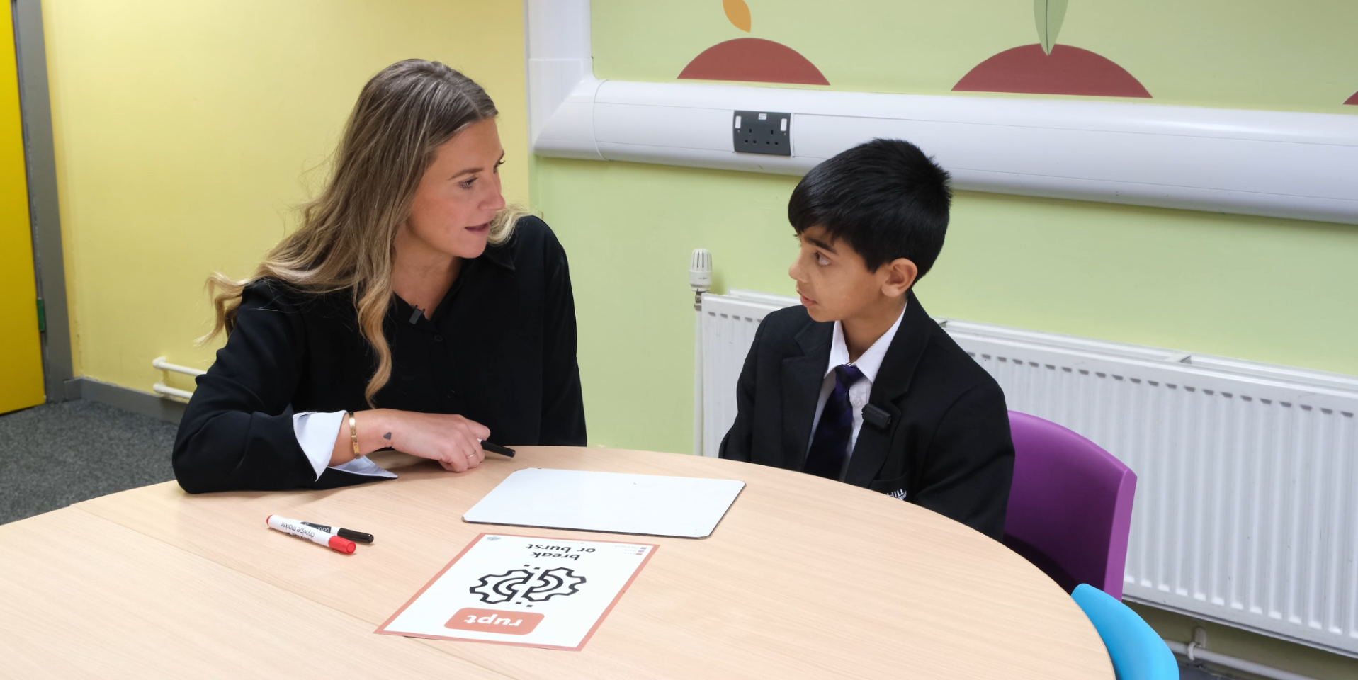 An educator and young person at a table with a worksheets
